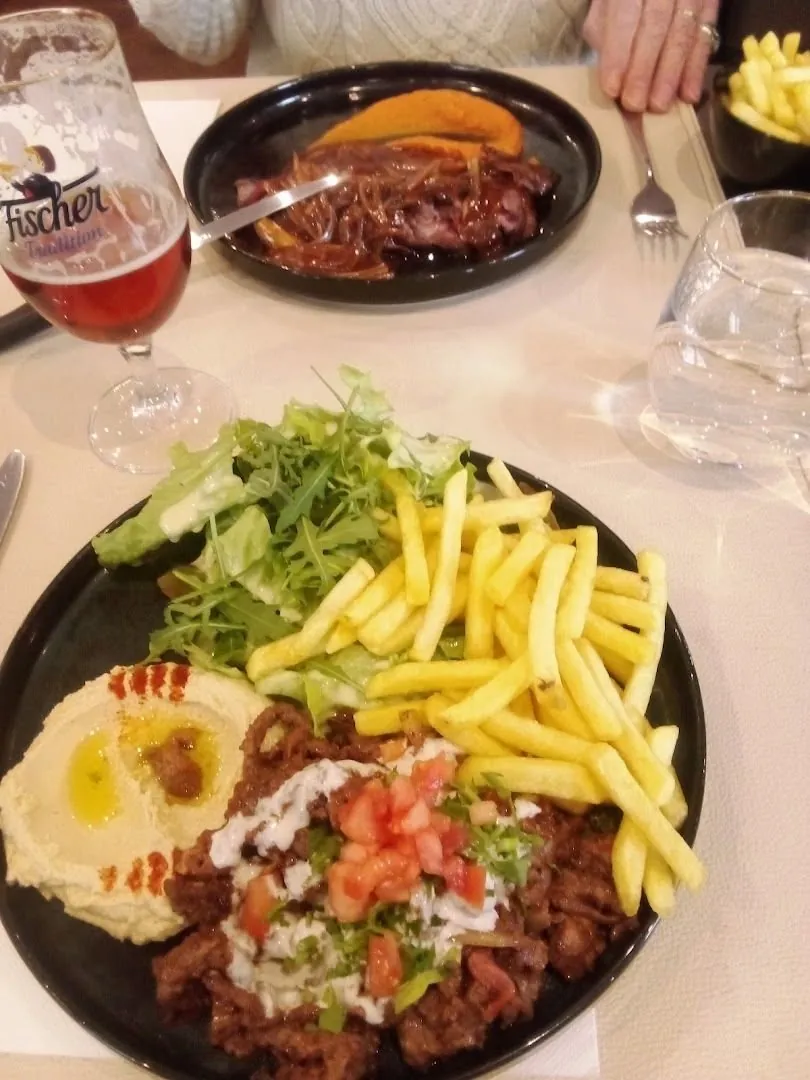 Une assiette avec houmous et frites, et un verre de bière Fischer